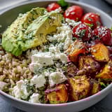 Warm Customizable Grain Bowl featuring chicken and chickpeas over brown rice, topped with feta and fresh herbs.
