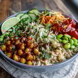 Diced cucumbers, cherry tomatoes, and edamame mingle with peanuts over brown rice in this fresh Peanut Chickpea Protein Bowl.