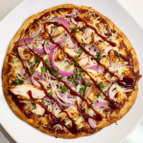 Golden-baked Chicken BBQ Pizza slices showing red onions and fresh cilantro garnish.