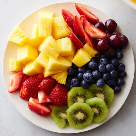 Colorful bowl of fresh Fruit Salad with strawberries, kiwi, and blueberries, glistening with citrus syrup.