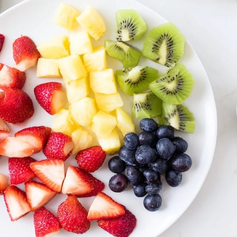 Glistening Fruit Salad in a glass bowl with vibrant pineapple chunks and juicy halved grapes.
