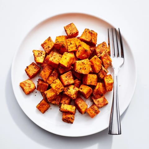 Seasoned sweet potato cubes roasted to tender perfection on a baking sheet.