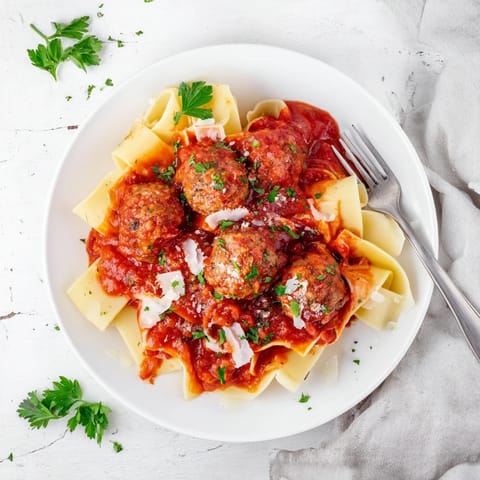 Tender turkey meatballs on a baking tray next to a bowl of tomato sauce, showing the easy preparation steps for a healthy, oven-baked family meal.