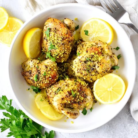 Golden pan-seared Lemon Pepper Chicken breast slices resting on a plate with cracked pepper.