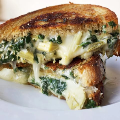 Perfectly grilled Spinach Artichoke Grilled Cheese on sourdough, served with a creamy tomato soup for a cozy lunch.  