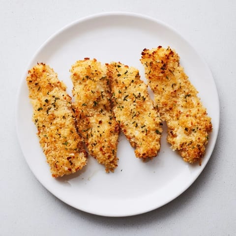 Freshly baked Crispy Panko Chicken Strips served on a white plate with a side of creamy ranch dip.