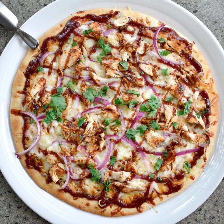 Homemade Chicken BBQ Pizza with smoky barbecue sauce and grilled chicken on a wooden board.