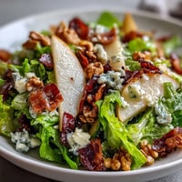 Crispy prosciutto shards rest atop frisée, pear, blue cheese, and crispy prosciutto salad with toasted walnuts.